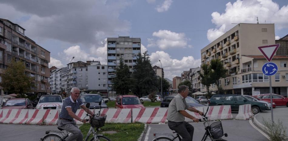 Los albaneses de Kosovo andan en bicicleta a lo largo del puente del río Ibar en la ciudad de Mitrovica, el 26 de agosto de 2022. Armando NIMANI / AFP