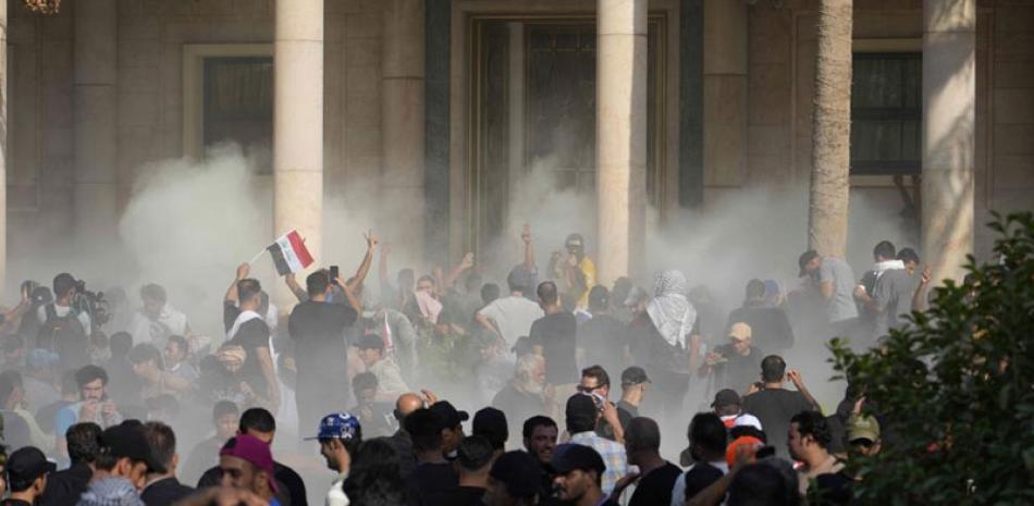 Elementos de las fuerzas de seguridad iraquíes lanzan gas lacrimógeno a los partidarios del clérigo chi. ap