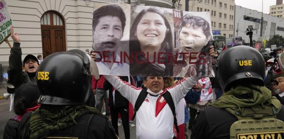 Un opositor del presidente Pedro Castillo muestra fotos de este, la cuñada Yenifer Paredes y su esposa Lilia Paredes con la leyenda “Delincuentes”, el domingo pasado. ap