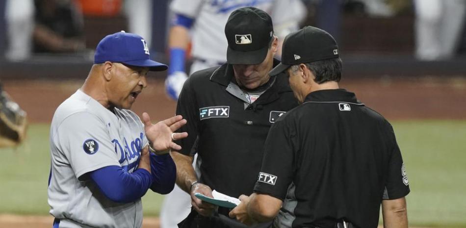 El mánager de los Dodgers, Dave Roberts, conversa con los umpire Ángel Hernández y James Hoye. Foto: AP.