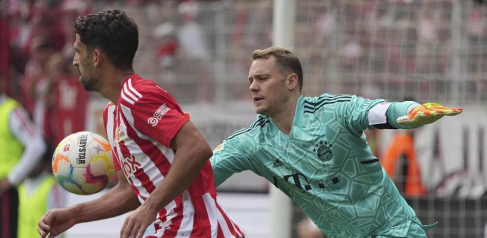 El portero de Bayern Munich, Manuel Neuer, derecha, y Rani Khedira de Unión Berlin disputan un balón durante un partido de la Bundesliga en el estadio Alte Forsterei.