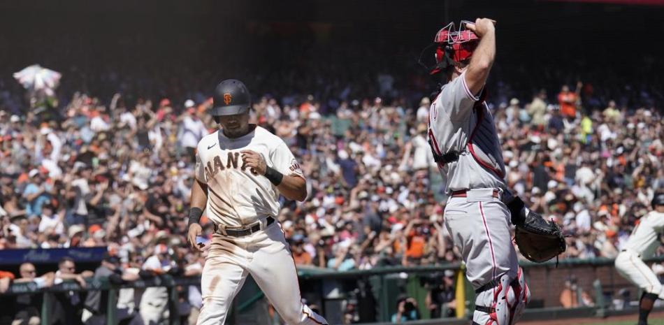 LaMonte Wade Jr., de los Gigantes, anota ante el receptor de los Filis J.T. Realmuto durante la tercera entrada del partido del sábado en San Francisco.