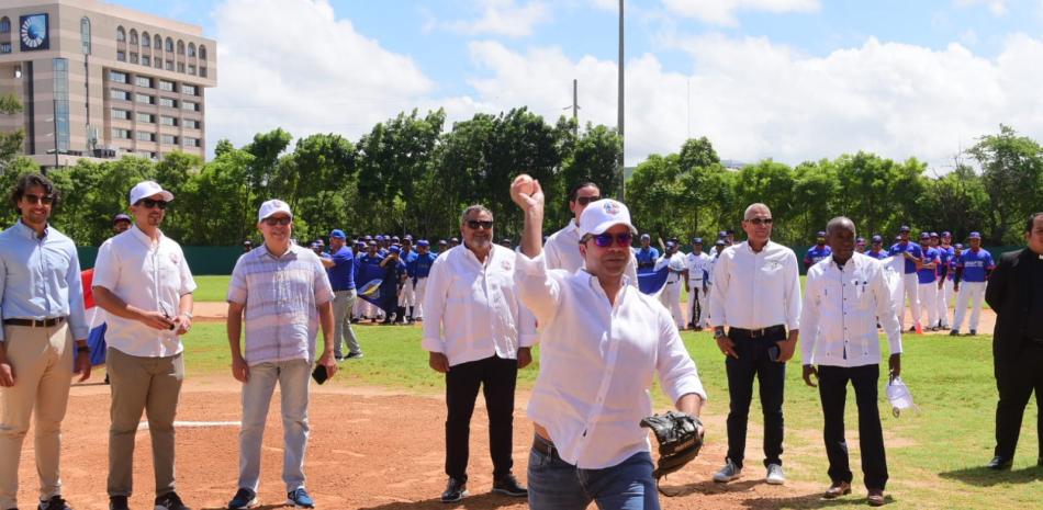 Samuel Pereyra, administrador de BanReservas realiza el pitcheo simbólico que dejó inaugurada la Liga de Béisbol Universitario. Detrás figura Junior Noboa, Comisionado Nacional de Béisbol y varias de las personalidades asistentes.