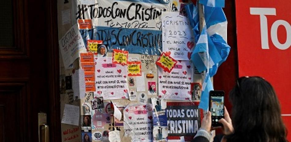 Una mujer toma fotografías de carteles dejados por simpatizantes de la vicepresidenta argentina Cristina Fernández de Kirchner afuera de su residencia en Buenos Aires. Foto: AFP Forum.