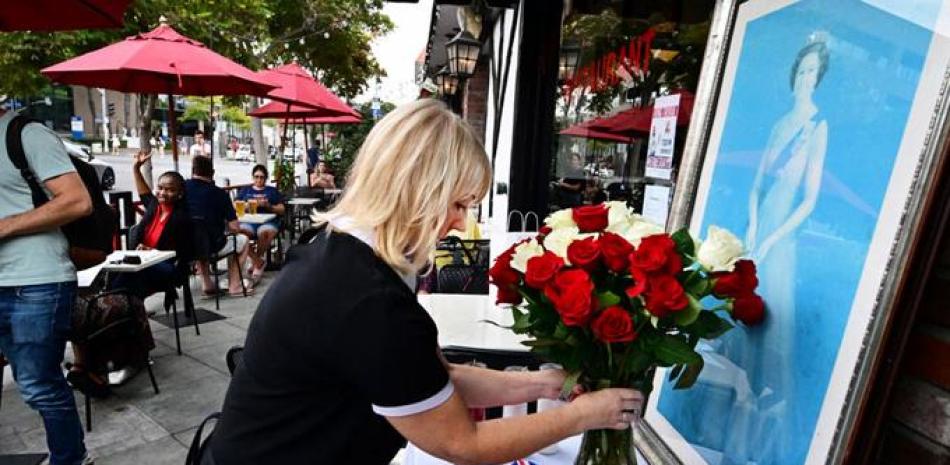 Christine MaIntosh coloca ramos de flores sobre una bandera y frente a un retrato de la reina isabel II, ayer prente a un pub en Santa Mónica, California.  afp