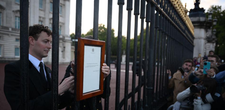 Personal anuncia el fallecimiento de la reina Isabel II en la verja del Palacio de Buckinham en Londres, ayer.  ap