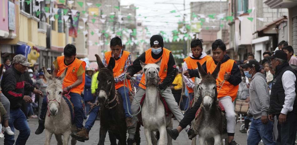 Varios chicos compiten en una prueba eliminatoria para la carrera de burros durante un festival anual de estos equinos en Salcedo, Ecuador, el sábado 10 de septiembre de 2022. (AP Photo/Dolores Ochoa)