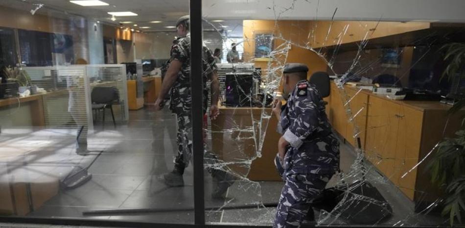Policías libaneses entran a un banco a través de una ventana que rompieron depositantes al salir luego de tratar de obtener su dinero, en Beirut. ap