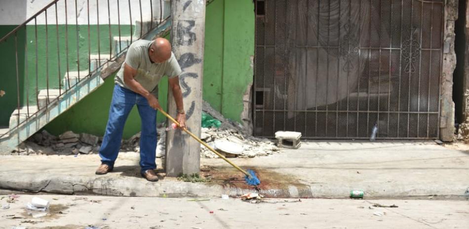 Un hombre limpia los rastros de sangres donde cayeron abatidos las personas que fueron ultimadas en Romana. Foto: Jorge Martínez/LD.