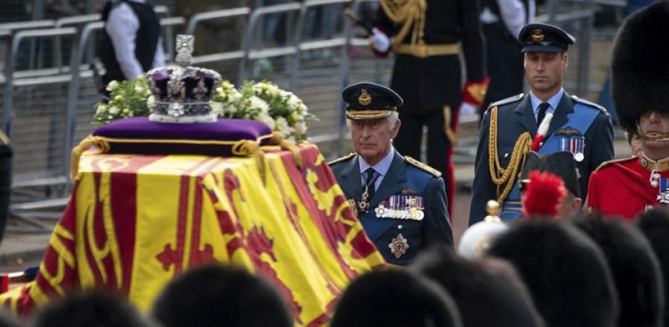 El rey Carlos III y el príncipe Guillermo siguen el ataúd de la reina Isabel II cubierto con la bandera real, portado en un carro con caballos en la procesión ceremonial desde el Palacio de Buckingham a la Sala Westminster del Parlamento, Londres, antier. ap
