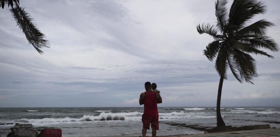 Un hombre carga a su hijo en la costa atlántica de Nagua, en la provincia María Trinidad Sánchez, durante la tarde del domingo. Erika Santelices/AFP.