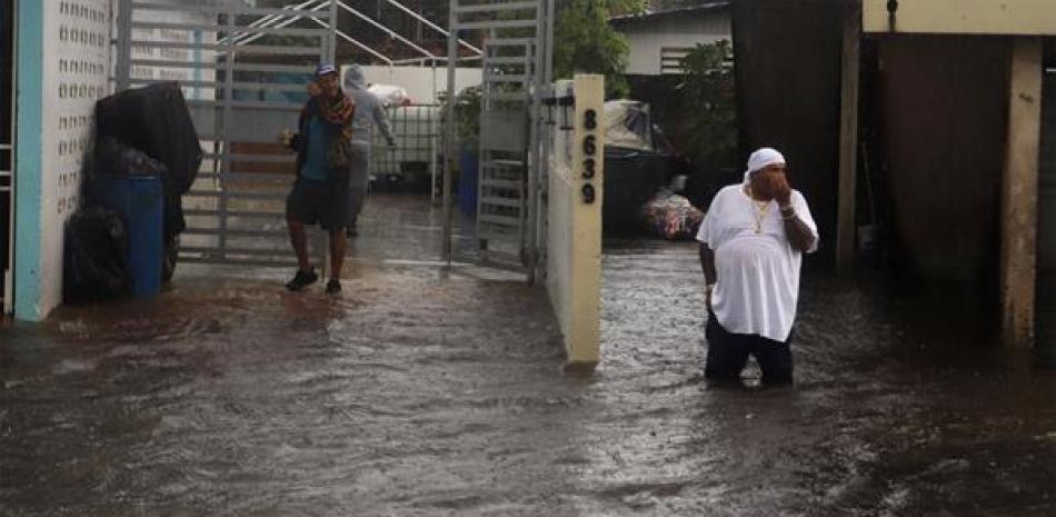 Personas caminan en una calle inundada debido a lluvias ocasionadas por el paso del huracán Fiona hoy, en Toa Baja (Puerto Rico). 

Foto: EFE/Thais LLorca