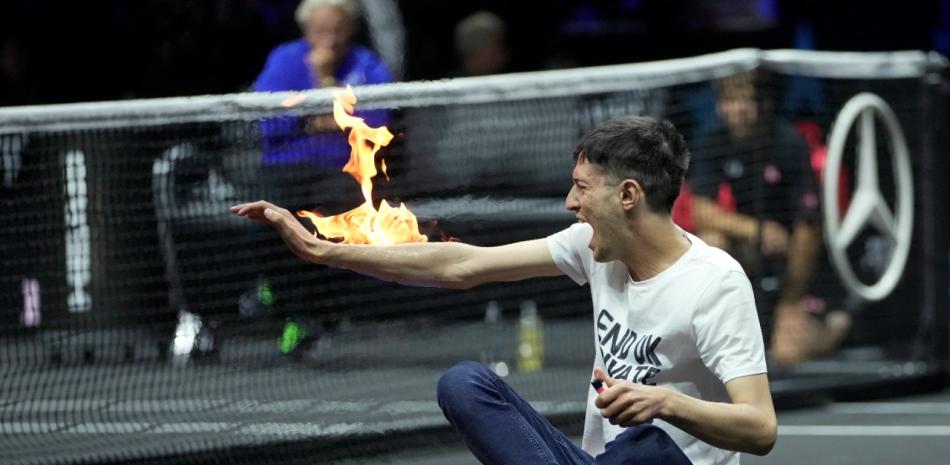 Un hombre se prende fuego en la mano durante una protesta en el partido Diego Schwartzman del Team World contra Stefanos Tsitsipas del Team Europe el primer día del torneo de tenis Laver Cup en el O2 de Londres, el viernes 23 de septiembre de 2022. Foto: AP/Kin Cheung.