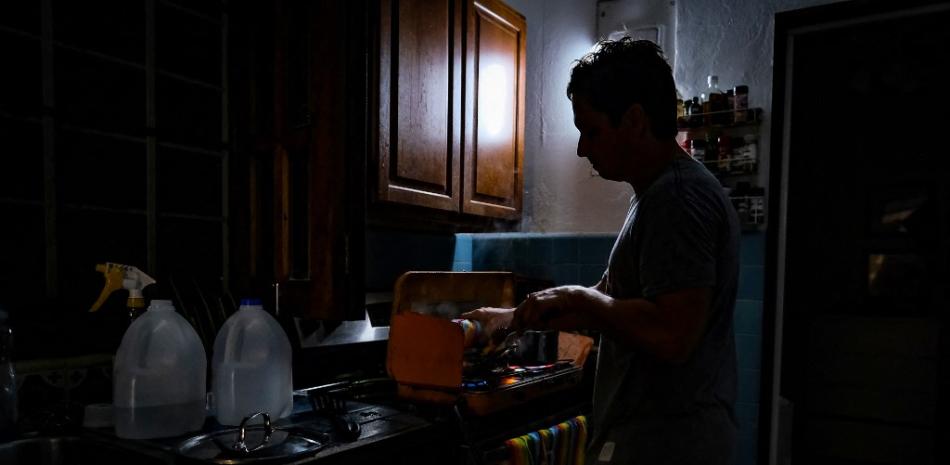 Una persona cocina a oscuras en una casa de la comunidad Condado de Santurce en San Juan, Puerto Rico, el 19 de septiembre de 2022, después de que se fuera la luz con el paso del huracán Fiona. Foto: AFP.