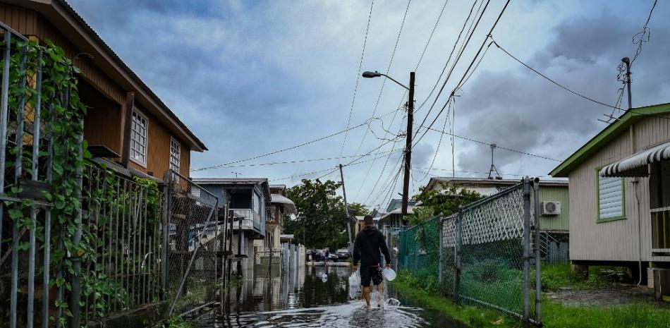 Un hombre camina por una calle inundada en el barrio Juana Matos de Catano, Puerto Rico, el 19 de septiembre de 2022, tras el paso del huracán Fiona. Foto: AFP.