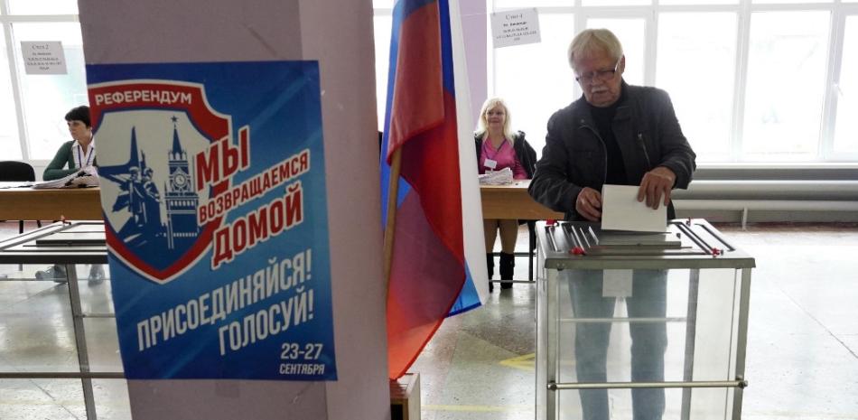 Un hombre deposita su voto para el referéndum en un colegio electoral de Mariupol el 27 de septiembre de 2022. Foto: AFP.