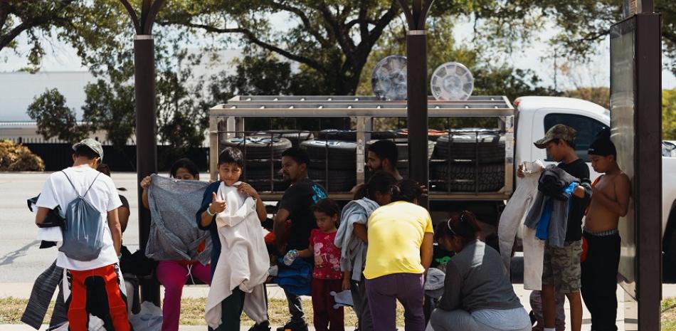 Un grupo de migrantes venezolanos se sienta en una parada de autobús frente al Centro de Recursos para Migrantes después de que expirara su estadía de tres días en el refugio el 19 de septiembre de 2022 en San Antonio, Texas. AFP.