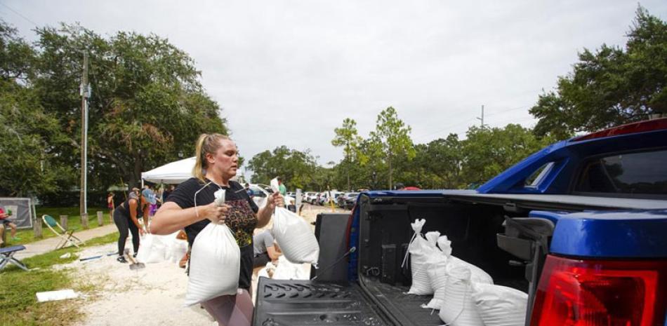 Victoria Colson, de 31 años, carga sacos de arena en su camioneta junto con otros residentes de Tampa que esperaron unas dos horas en el Complejo Himes Avenue para llevarse 10 sacos gratuitos, antier. ap