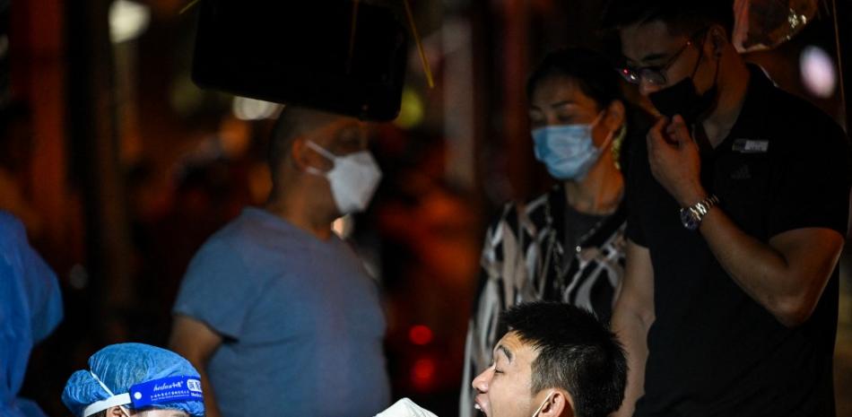 Un trabajador de la salud toma una muestra de hisopo de un hombre para detectar el coronavirus Covid-19 en el distrito de Jingan de Shanghái. Héctor RETAMAL / AFP