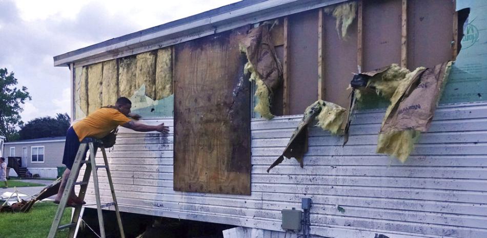 Iván Mendoza comienza a reparar daños en su casa móvil en Davie, Florida, la madrugada del miércoles 28 de septiembre de 2022. Foto AP.