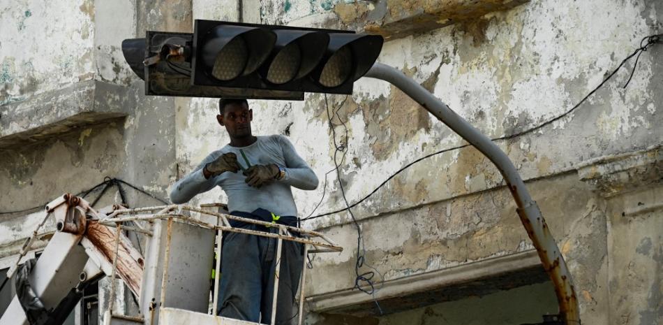 Un hombre repara un semáforo en La Habana, el 29 de septiembre de 2022, tras el paso del huracán Ian. Cuba superó las 12 horas del pasado miércoles en apagón total con “generación eléctrica cero” por fallas en los enlaces del Sistema Eléctrico Nacional (Sen), tras el paso del poderoso huracán Ian. YAMIL LAGE / AFP