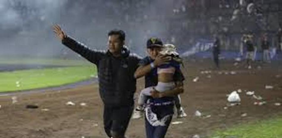 Un zimpatizante camina junto a un niño en el estadio luego de los disturbios ocurridos en un partido de fútbol este fin de semana