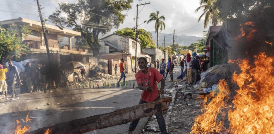 Un hombre agrega leña al fuego que arde en las calles mientras los manifestantes protestan para exigir la renuncia del primer ministro Ariel Henry, en el área de Petion-Ville de Port-au-Prince, Haití, el 3 de octubre de 2022. Las protestas se pusieron en marcha después de que el primer ministro Ariel Henry anunciara que el gobierno con problemas de liquidez ya no podía pagar los subsidios al combustible y que los precios tendrían que aumentar. Richard Pierrin / AFP