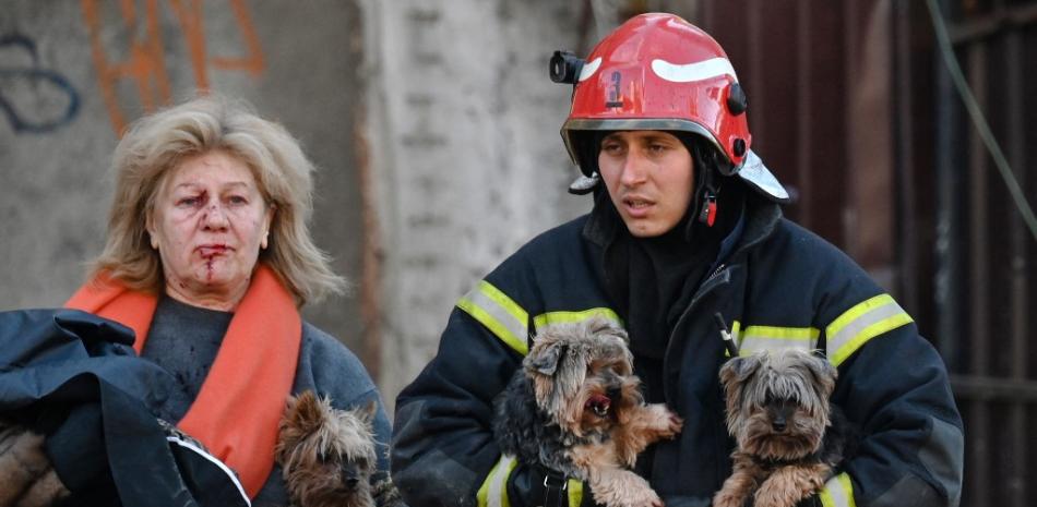 Un trabajador de emergencia lleva perros mientras escolta a un residente local fuera de un edificio de oficinas de varios pisos parcialmente destruido después de que varios ataques rusos golpearon la capital ucraniana de Kyiv el 10 de octubre de 2022, en medio de la invasión rusa de Ucrania.
Serguéi SUPINSKY / AFP