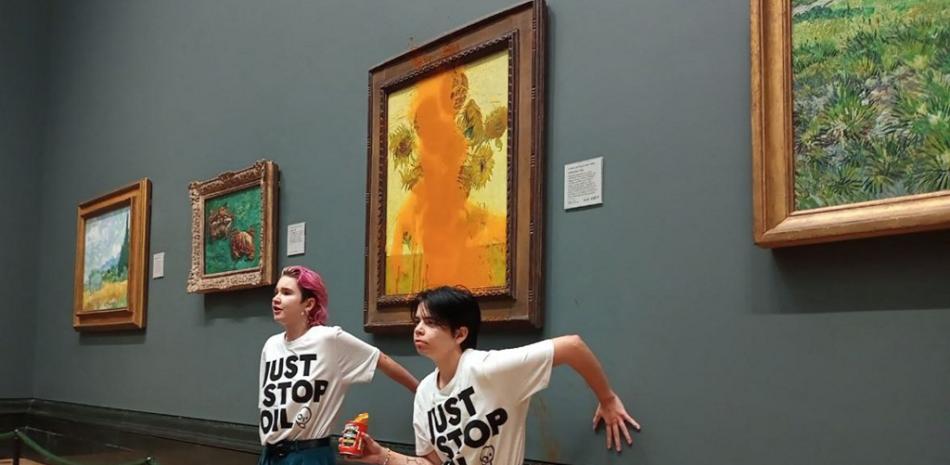 Una foto del grupo de campaña climática Just Stop Oil muestra a los activistas con las manos pegadas a la pared debajo de los "Girasoles" de Vincent van Gogh después de arrojar sopa de tomate sobre la pintura en la Galería Nacional en el centro de Londres el 14 de octubre de 2022. Policía Metropolitana de Londres dijo que sus oficiales arrestaron a dos manifestantes del grupo Just Stop Oil por daños criminales y allanamiento de morada con agravantes después de que "arrojaron una sustancia sobre una pintura" en la galería de Trafalgar Square.
Folleto / Just Stop Oil / AFP