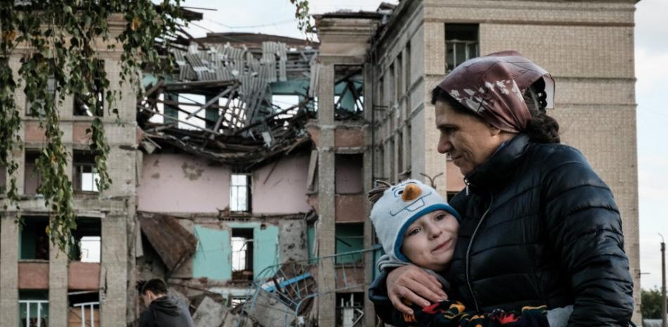 Olga Srednyakova (derecha), de 51 años, madre soltera de ocho hijos, abraza a la hija menor, Vera, de 8 años, mientras otros cosechan hongos en un terreno abandonado de su escuela destruida en Konstantinovka, en la región de Donetsk, el 13 de octubre de 2022, en medio de la invasión rusa de Ucrania.
Yasuyoshi CHIBA / AFP