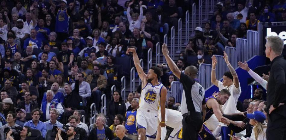 Stephen Curry, de los Warriors, observa la trayectoria del balón para encestar un triple en la victoria sobre los Lakers de Los Angeles.