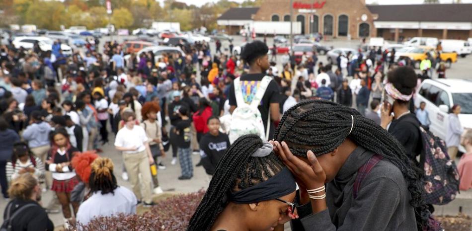 Los estudiantes se paran en un estacionamiento cerca de la Escuela Secundaria Central de Artes Visuales y Escénicas después de un tiroteo reportado en la escuela en St. Louis el lunes 24 de octubre de 2022. AP