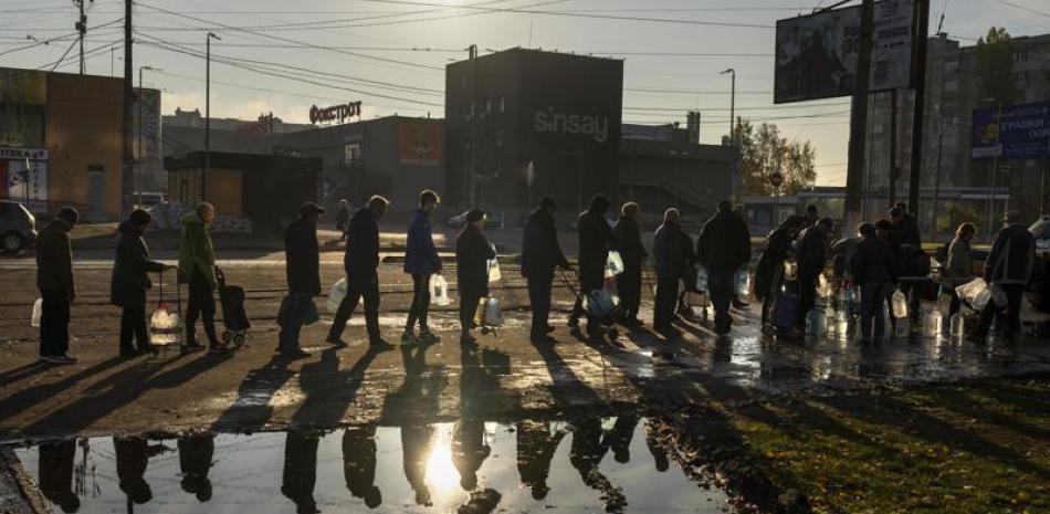 Unas personas se forman para llenar botellas de plástico con agua potable de un tanque en el centro de Mykolaiv, Ucrania, el lunes 24 de octubre de 2022. (AP Foto/Emilio Morenatti)