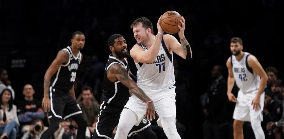 Kyrie Irving, de los Nets de Brooklyn, defiende a Luka Doncic, de los Mavericks, en acción del partido del jueves por la noche en el baloncesto de la NBA.