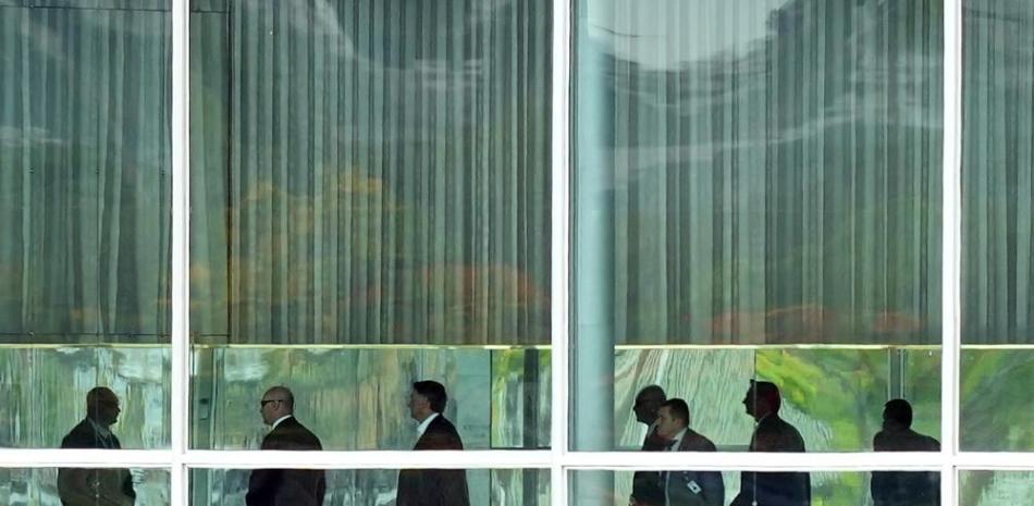 El presidente brasileño Jair Bolsonaro, tercero de izquierda a derecha, abandona su residencia oficial, el Palacio de la Alvorada, para dirigirse a su oficina en el Palacio de Planalto, en Brasilia, el lunes 31 de octubre de 2022. (AP Foto/Eraldo Peres)