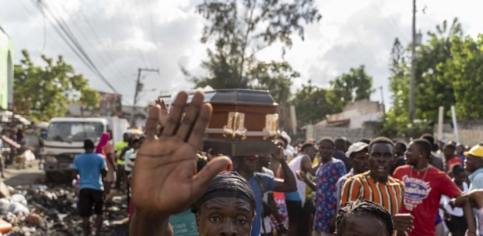 La gente lleva un ataúd mientras otros protestan durante una manifestación contra el primer ministro haitiano Ariel Henry y las Naciones Unidas en medio de una crisis de salud y seguridad en Port-au-Prince el 21 de octubre de 2022. AFP