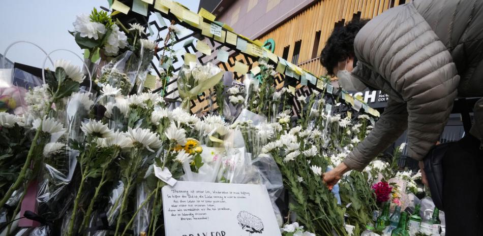 Una mujer coloca una flor para rendir homenaje a las víctimas de un accidente mortal después de las festividades de Halloween del sábado por la noche en la calle cerca de la escena en Seúl, Corea del Sur, el martes 1 de noviembre de 2022. AP.