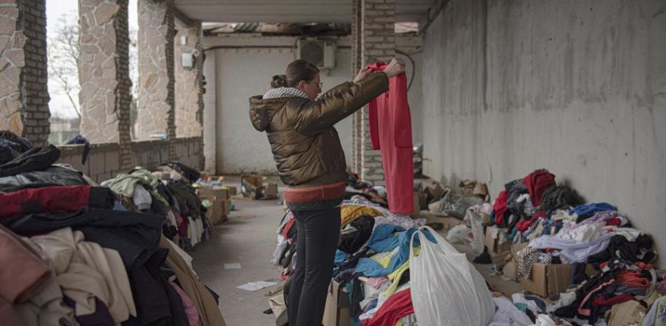 Kateryna, de 36 años, empleada de la cocina de la maternidad Puscha Vodytsia, busca ropa en el espacio de distribución en la aldea de Moshun, afueras de Kiev, Ucrania, viernes 4 de noviembre de 2022. (AP Foto/Andrew Kravchenko)