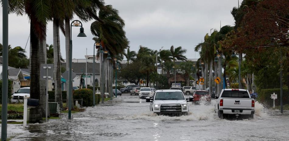 Los vehículos circulan por una calle inundada después de que el huracán Nicole tocara tierra el 10 de noviembre de 2022 en Fort Pierce, Florida. AFP.