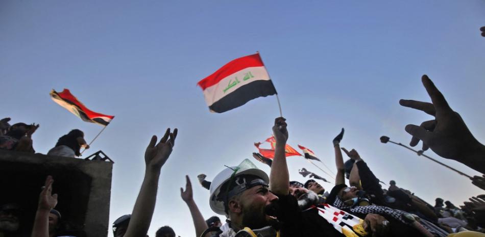 En esta foto de archivo los manifestantes iraquíes corean consignas y agitan las banderas nacionales de su país durante las manifestaciones antigubernamentales en curso en la plaza Tahrir en la capital Bagdad, el 30 de octubre de 2019. Foto: Ahmad Al-Rubaye/AFP.