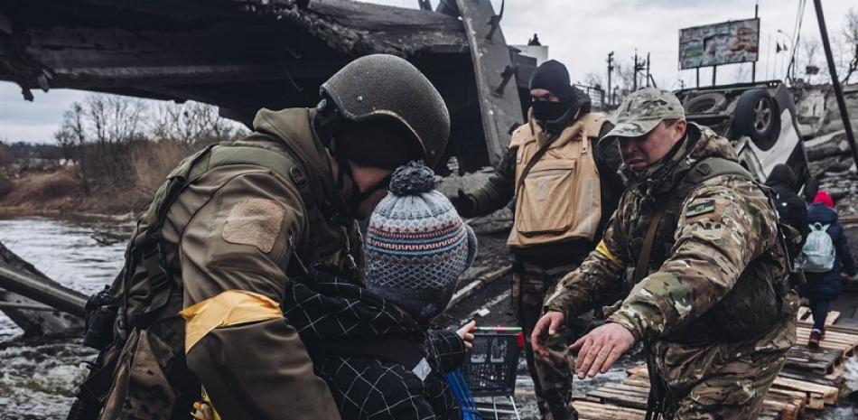 Unos soldados ayudan a cruzar el río a un niño, a 7 de marzo de 2022, en Irpin (Ucrania). - Diego Herrera - Europa Press