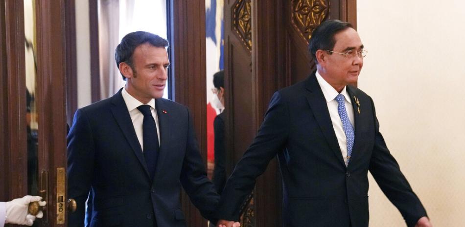 El primer ministro de Tailandia, Prayuth Chan-ocha (derecha), camina de la mano con el presidente de Francia, Emmanuel Macron, antes de una reunión en Bangkok, Tailandia, el 17 de noviembre de 2022. (AP Foto/Sakchai Lalit, Pool)
