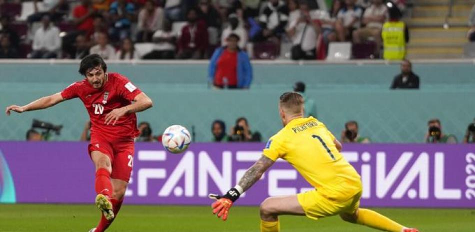 Sardar Azmoun de Irán, a la izquierda, patea el balón durante el partido de fútbol del grupo B de la Copa Mundial entre Inglaterra e Irán en el Estadio Internacional Khalifa en Doha, Qatar, el lunes 21 de noviembre de 2022. AP.