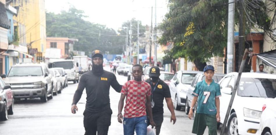 Dos oficiales de Migración conducen detenido a un haitiano en el Distrito Nacional, en el marco de las redadas que se han intensificado en los últimos días . / Jorge Martínez / Listín Diario
