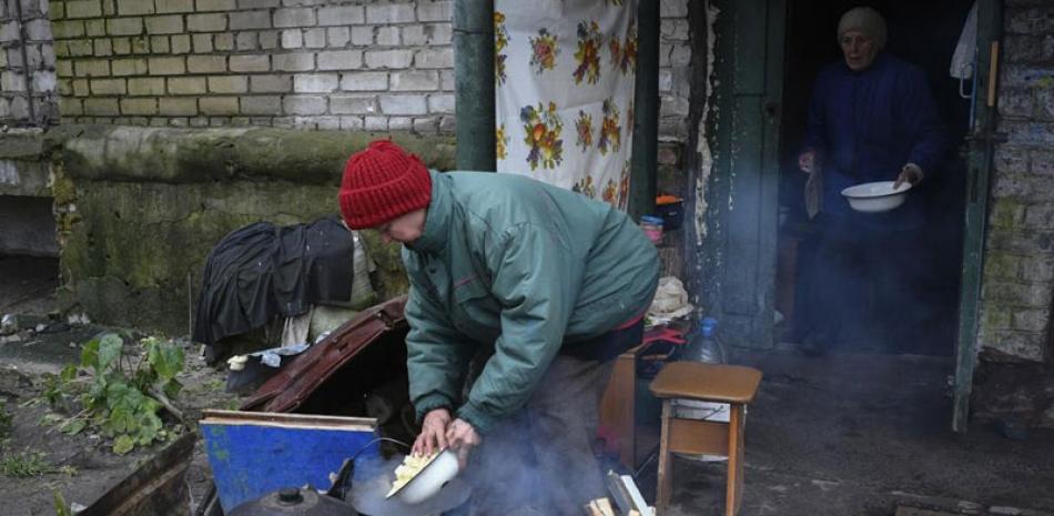 Ancianas cocinan en una hoguera en el patio de un edificio de apartamentos en Lyman, en la región de Donetsk, Ucrania, el domingo 20 de noviembre de 2022. AP