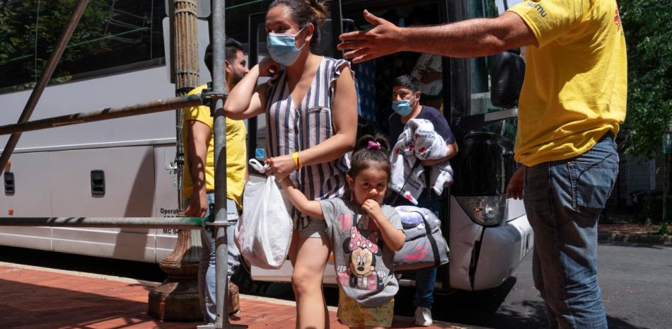 Los migrantes Silvia Moreno del Castillo (cen) de Lima, Perú, con su hija Brisa y su esposo Gerardo Puente, siendo recibidos por Derick Alegria (i) y Orlando Andara del grupo SAMU First Response, en Washington el 11 de agosto del 2022. (Foto AP/Jacquelyn Martin)