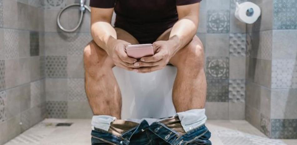 Persona usando el teléfono en el baño.