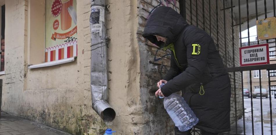 Kateryna Luchkina, una trabajadora de 31 años del Departamento de Salud de Kyiv, recoge agua de lluvia de un desagüe en Kyiv, Ucrania, el jueves. 24 de noviembre de 2022. Los residentes de la capital de Ucrania, bombardeada pero no intimidada, deambulaban por las calles con botellas vacías en busca de agua y se aglomeraban en los cafés en busca de calor, luz y energía el jueves, cambiando desafiantemente al modo de supervivencia después de que los nuevos ataques con misiles rusos el día anterior se hundieron. la ciudad de 3 millones y gran parte del país en la oscuridad en invierno. (Foto AP/John Leicester