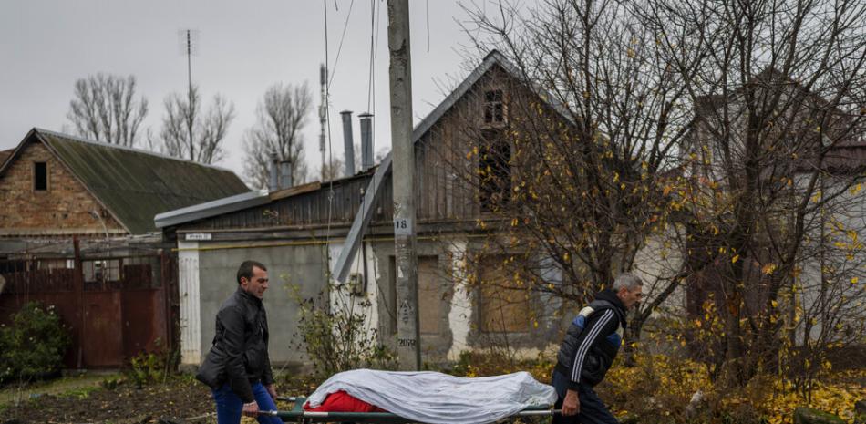 Trabajadores municipales recogen el cuerpo de un hombre en Kherson, en el sur de Ucrania, el viernes 25 de noviembre de 2022. El hombre murió durante un ataque ruso el jueves. (Foto AP/Bernat Armangue).