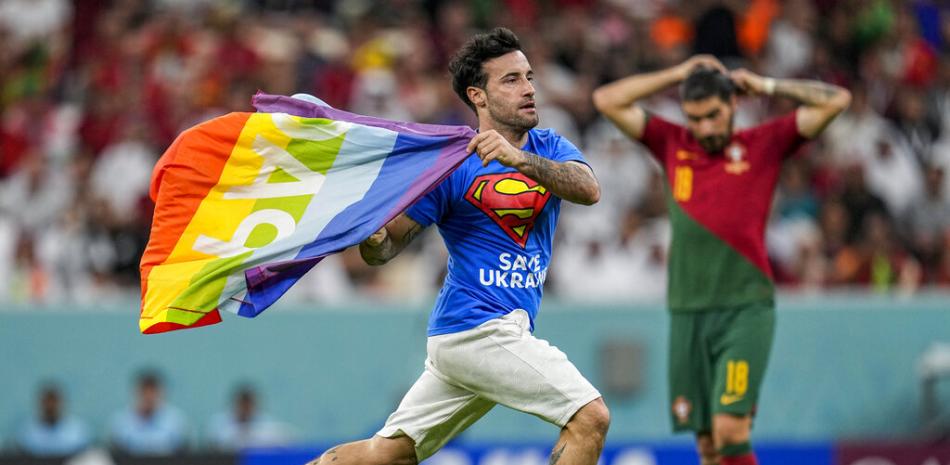 Un invasor de la cancha corre por el campo con una bandera del arcoíris durante el partido de fútbol del grupo H de la Copa Mundial entre Portugal y Uruguay, en el Estadio Lusail en Lusail, Qatar, el lunes 28 de noviembre de 2022. (Foto AP/Abbie Parr)